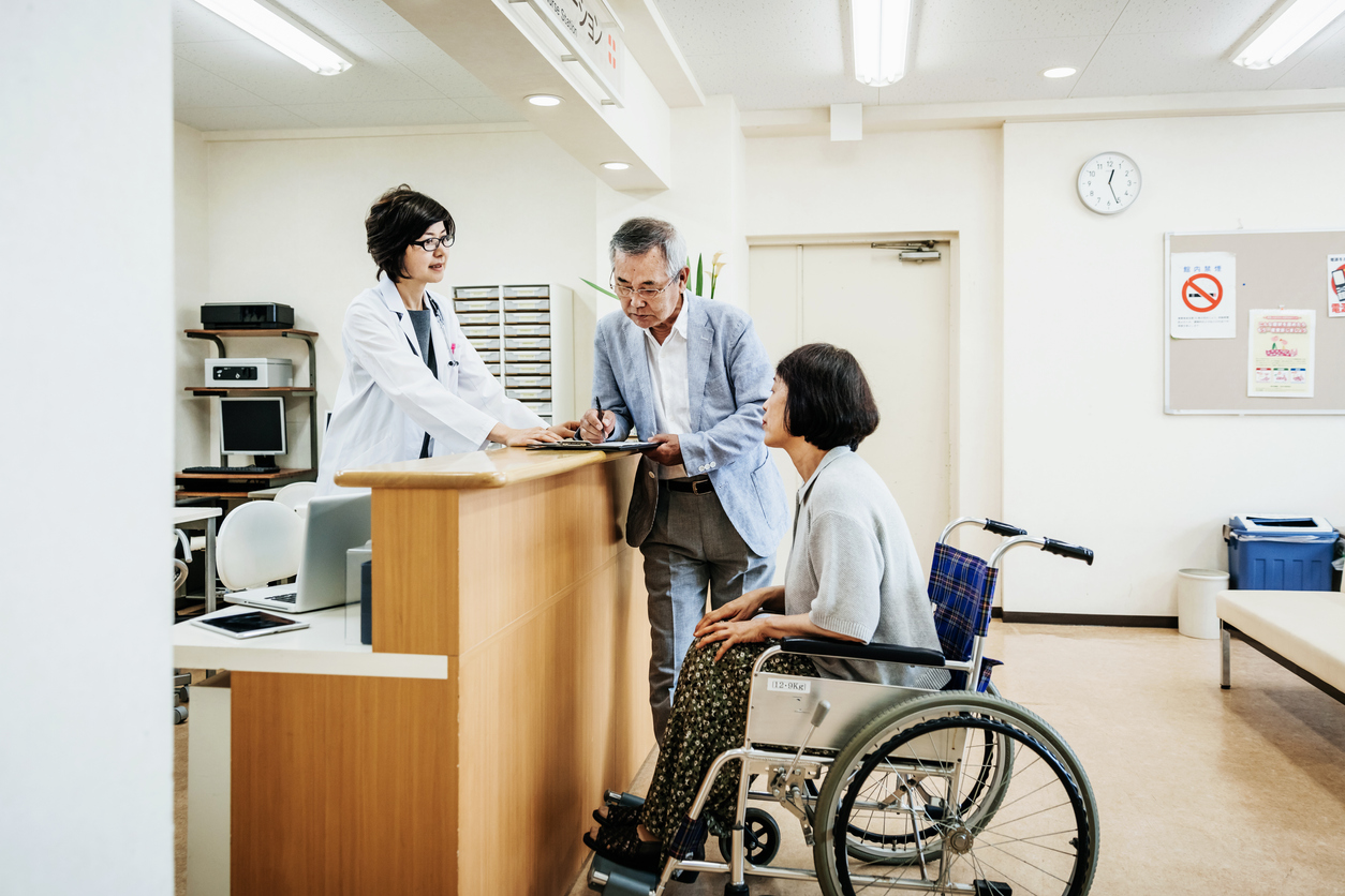 Nurse Helping Elderly Couple At Hospital Counter